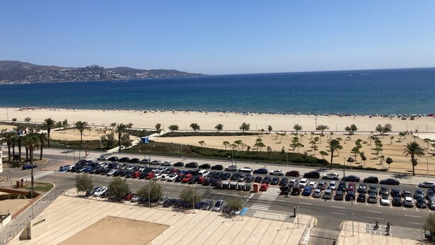 A beach with a parking lot in the foreground and a clear view of the ocean. - Comfortable flat in EmpuriaBrava by the strand with a stunning view on the bay. (Ampuriabrava)