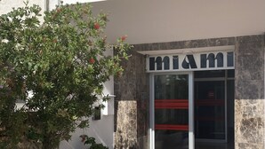 A building entrance with a 'Miami' sign, a glass door, and a tiled pavement. - Comfortable flat in EmpuriaBrava by the strand with a stunning view on the bay. (Ampuriabrava)