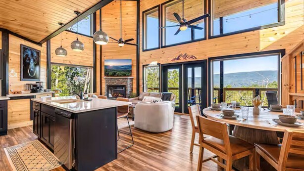 A spacious kitchen with a central island, a dining area with a round table, and large windows offering mountain views. - OMG A Bear (Sevierville)
