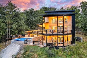 Eine mehrstöckige Holzhütte mit Schwimmbad, umgeben von Bäumen.