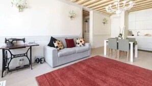 A modern living room with a grey sofa, a red rug, and a sewing machine. - Enchanting flat, in the core of Treviso, the city of Prosecco, pet friendly (Treviso)