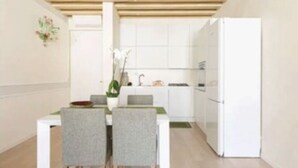 A compact kitchen with white cabinets, a white refrigerator, and a dining table with four chairs. - Enchanting flat, in the core of Treviso, the city of Prosecco, pet friendly (Treviso)