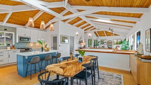 A spacious kitchen with white cabinets, a central island, and a wooden ceiling. - Island Chic - Zen Retreat - A/C in 2 Bedrooms (Princeville)