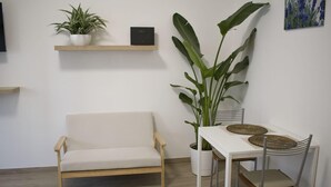A modern living room with a sofa, a dining table with chairs, and potted plants. - Maison 27 Holiday Home Cremona (CREMONA)