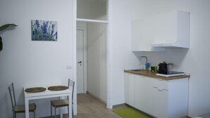 A compact kitchen with white cabinets, a wooden countertop, and a coffee machine. - Maison 27 Holiday Home Cremona (CREMONA)