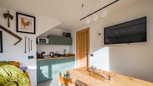A compact kitchen with a wooden table and chairs, a microwave, and a sink. - Chalet with sauna H 311 (GORDONA)