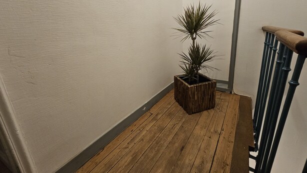 Eine Holztreppe mit einem Blumentopf im Zwischenpodest.