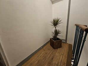 Eine Holztreppe mit einem Blumentopf im Zwischenpodest.