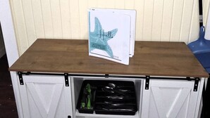 Ein Holztisch mit einem Schild, einer Schublade voller Utensilien und einer Leuchtturm-Dekoration an der Wand.