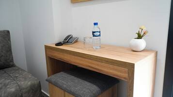 Un escritorio de madera con un teléfono, un vaso y una botella de agua.