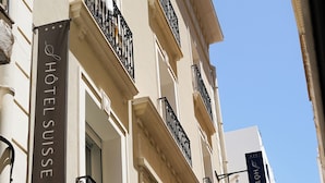 A building with balconies, a sign reading "HOTEL SUISSE," and a flag. - Hôtel Suisse (Tunis)