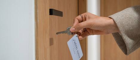 A hand holding a key and a hotel key card.