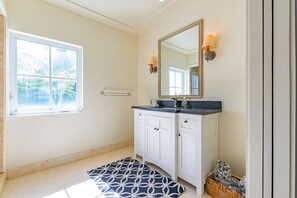 A bathroom with a window, a mirror, a sink, and a towel rack. - Caprice 8 - Luxury Ocean Front Villa - Pool (Nassau)