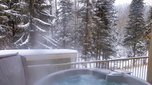 A hot tub on a balcony with a snowy forest view. - Lrg 1 Bedroom Suite -Bike Storage-Private Hot Tub! (Sun Peaks)