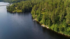 Un riu envoltat de bosc dens, amb un petit moll i una cabana.