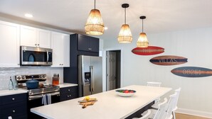 Cozinha moderna com armários brancos, eletrodomésticos de aço inoxidável e uma ilha central com bancadas.
