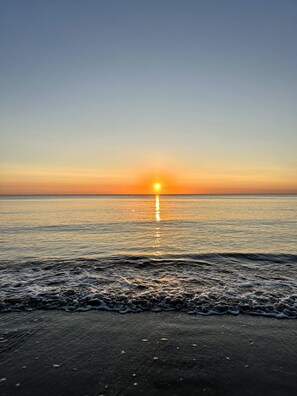 Une plage avec des vagues au coucher du soleil.