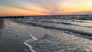 Uma praia com ondas e um píer ao longe.