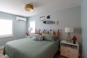 Une chambre à coucher comprenant un lit, des tables de chevet, une décoration murale représentant des poissons et un luminaire au plafond.