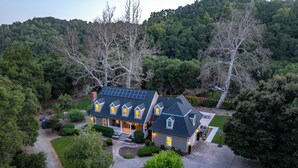 A large house with multiple windows, a driveway, and a well-maintained garden. - Luxe Westside 5BR/3.5BA w/Pool, Hot Tub, FirePit, Movie Room & more. (Templeton)