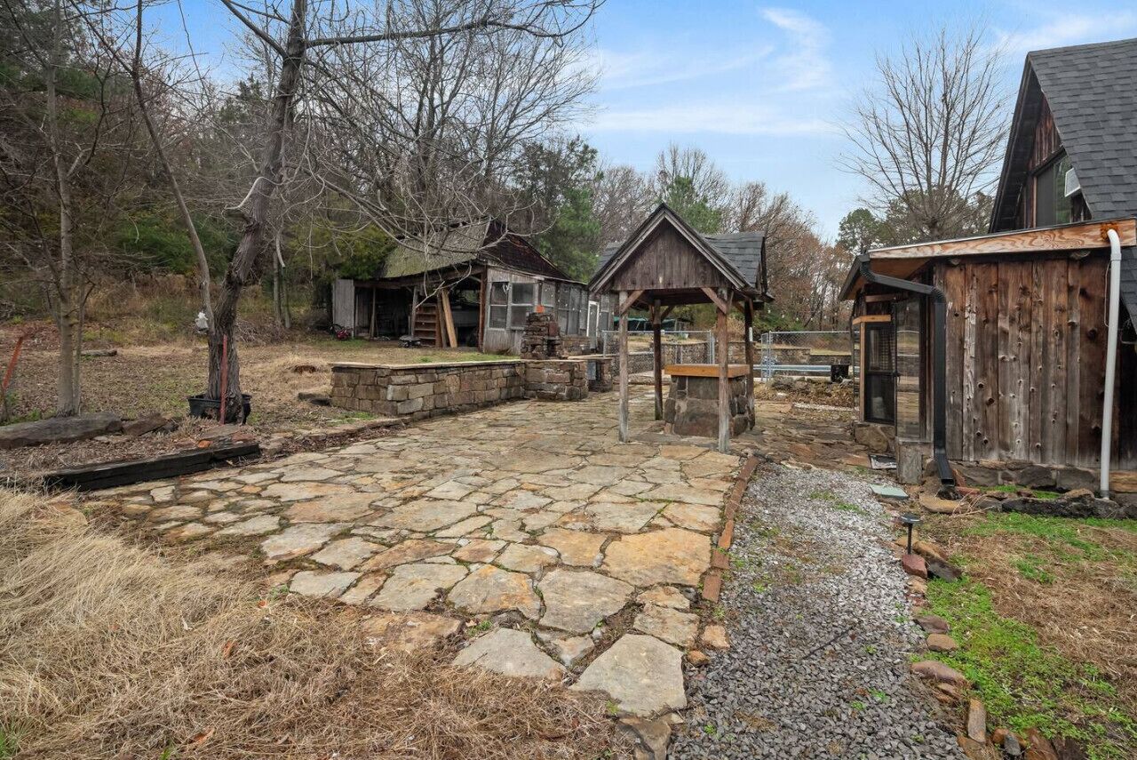 A rustic cabin area with stone pathways, wooden structures, and a stone building.