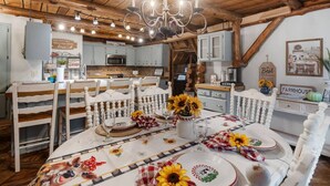 A rustic kitchen with wooden beams, a chandelier, and farmhouse-style decor. - Rustic Cabin with Modern Comfort – The Cuddly Cow in Rudy, AR (Rudy)