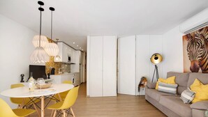 A modern living space with a dining area, sofa, and kitchen.