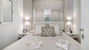 A modern bedroom with a large bed, two bedside tables, a mirror, and a window.