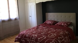 A bedroom with a bed, white wardrobe, and a dark headboard. - Beau Appartement Calme et Ensoleillé Parisdisney (Noisy-le-Grand)