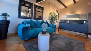 A modern living room with a teal sofa, a white side table with a plant, and a dark blue cabinet. - Lux Lodge near Piazza Erbe (Verona)