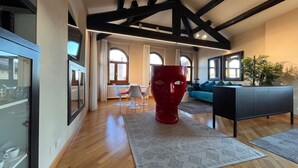 A spacious living area with wooden flooring, a red sculpture, a black sofa, and a grey cabinet. - Lux Lodge near Piazza Erbe (Verona)