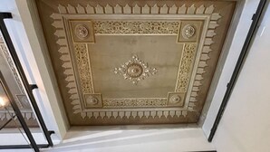 Een plafond met ingewikkelde bloem- en geometrische patronen, omlijst door een decoratieve rand.