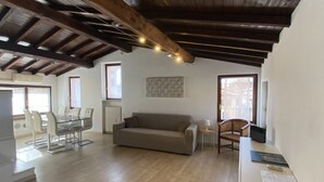 Amplia sala de estar con techo de madera, un sofá, una mesa de comedor con sillas y una pequeña mesita auxiliar.