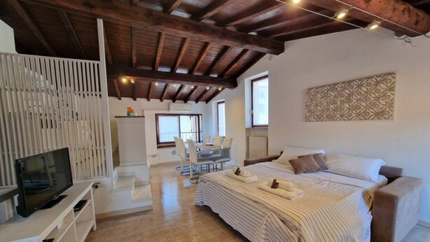 Un dormitorio amplio con una cama grande, un televisor sobre una consola blanca y un comedor con mesa y sillas.