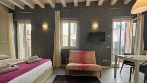 A hotel room with a bed, a chair, a desk, and a TV. - LOFT 17.2 - Verona Journeys (Verona)