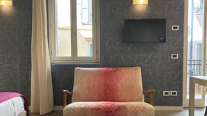 A room with a sofa, a bed, a TV mounted on the wall, and a window with curtains. - LOFT 17.2 - Verona Journeys (Verona)