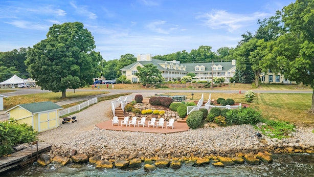 Un patio a la orilla del río con mesas al aire libre, un cobertizo pequeño y un muelle.