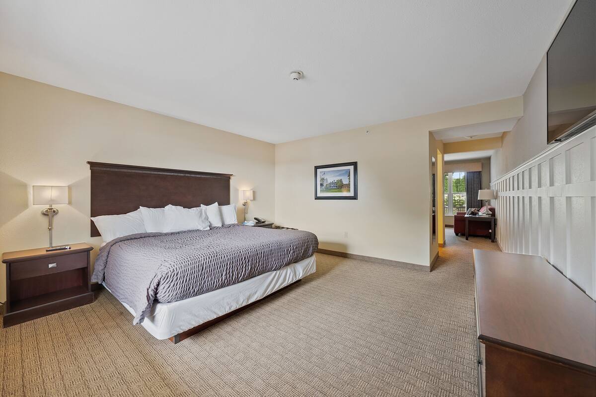 Une chambre d’hôtel avec un grand lit, une table de chevet, un bureau et une chaise.