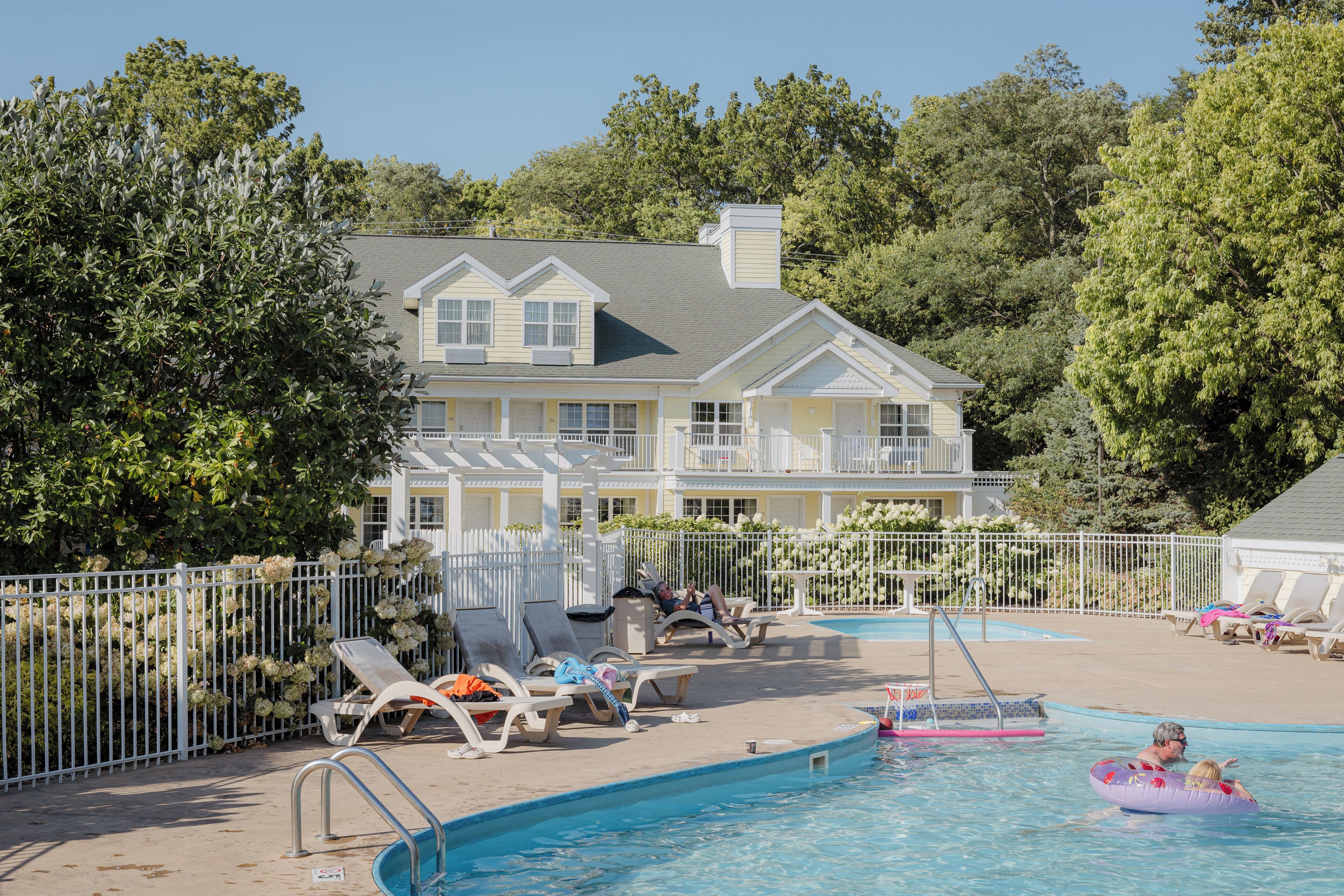 Ein Poolbereich mit Liegestühlen, einem Pool und einem Gebäude mit Balkon.