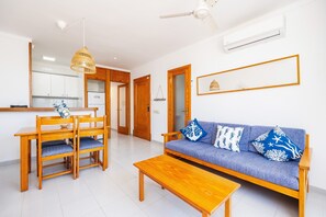 Un salon comprenant un canapé, des chaises en bois, une table basse, une table à manger et un ventilateur de plafond.