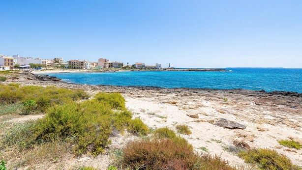 Una zona costera con edificios, un litoral rocoso y agua azul cristalina.
