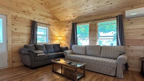 Een kamer met houten lambrisering, twee banken, een bijzettafeltje en grote ramen.