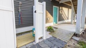 Une maison moderne dotée d’un porche abrité, d’une porte verte et d’un petit jardin.