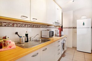 A kitchen with white cabinets, a wooden countertop, a sink, a microwave, and a refrigerator. - Holiday Apartment 'Ático Los Seres' with Sea View, Private Terrace & Wi-Fi (Los Cristianos)