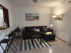 A living room with a sofa, coffee table, and chairs, a painting on the wall, and a lamp. - Holiday Apartment 'Ático Los Seres' with Sea View, Private Terrace & Wi-Fi (Los Cristianos)