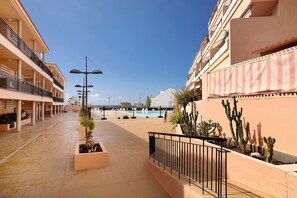 A hotel corridor with balconies, a pool, and cacti. - Holiday Apartment 'Ático Los Seres' with Sea View, Private Terrace & Wi-Fi (Los Cristianos)
