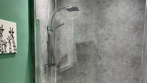 A modern bathroom with a glass-enclosed shower, a white bathtub, and a green wall. - Beautiful 3-bed House in Preston (Preston)