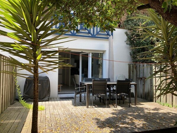 A patio with a table and chairs, a covered grill, and a sliding glass door leading to a covered area. - Apartment 'Cap-ferret Phare Ref 130' with Private Terrace (Lège-Cap-Ferret)