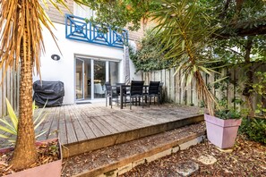 A wooden deck with outdoor furniture, a covered grill, and a potted plant. - Apartment 'Cap-ferret Phare Ref 130' with Private Terrace (Lège-Cap-Ferret)