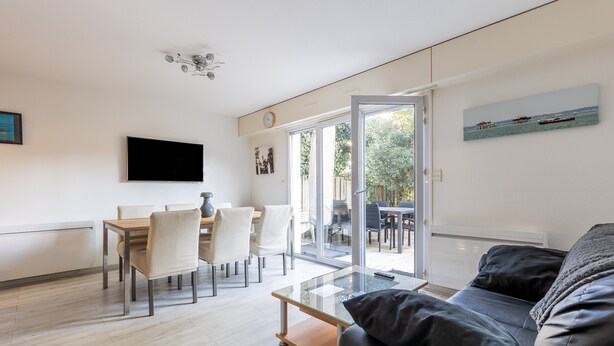 A modern living room with a glass coffee table, a black leather sofa, and a dining area with a wooden table and chairs. - Apartment 'Cap-ferret Phare Ref 130' with Private Terrace (Lège-Cap-Ferret)
